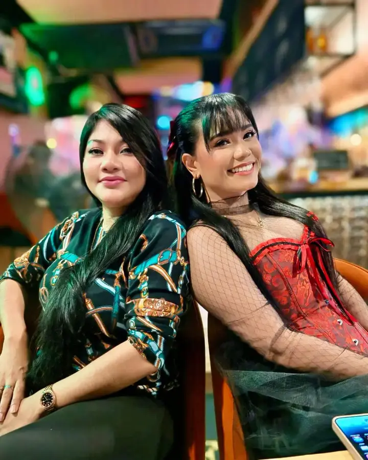 Two guests dressed up on a ladies night, neon bar behind