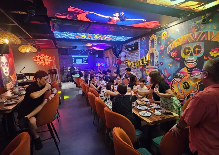 Packed La Vida dining room at night under neon lights